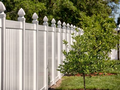 An image of a stylish white fence with pointed posts.